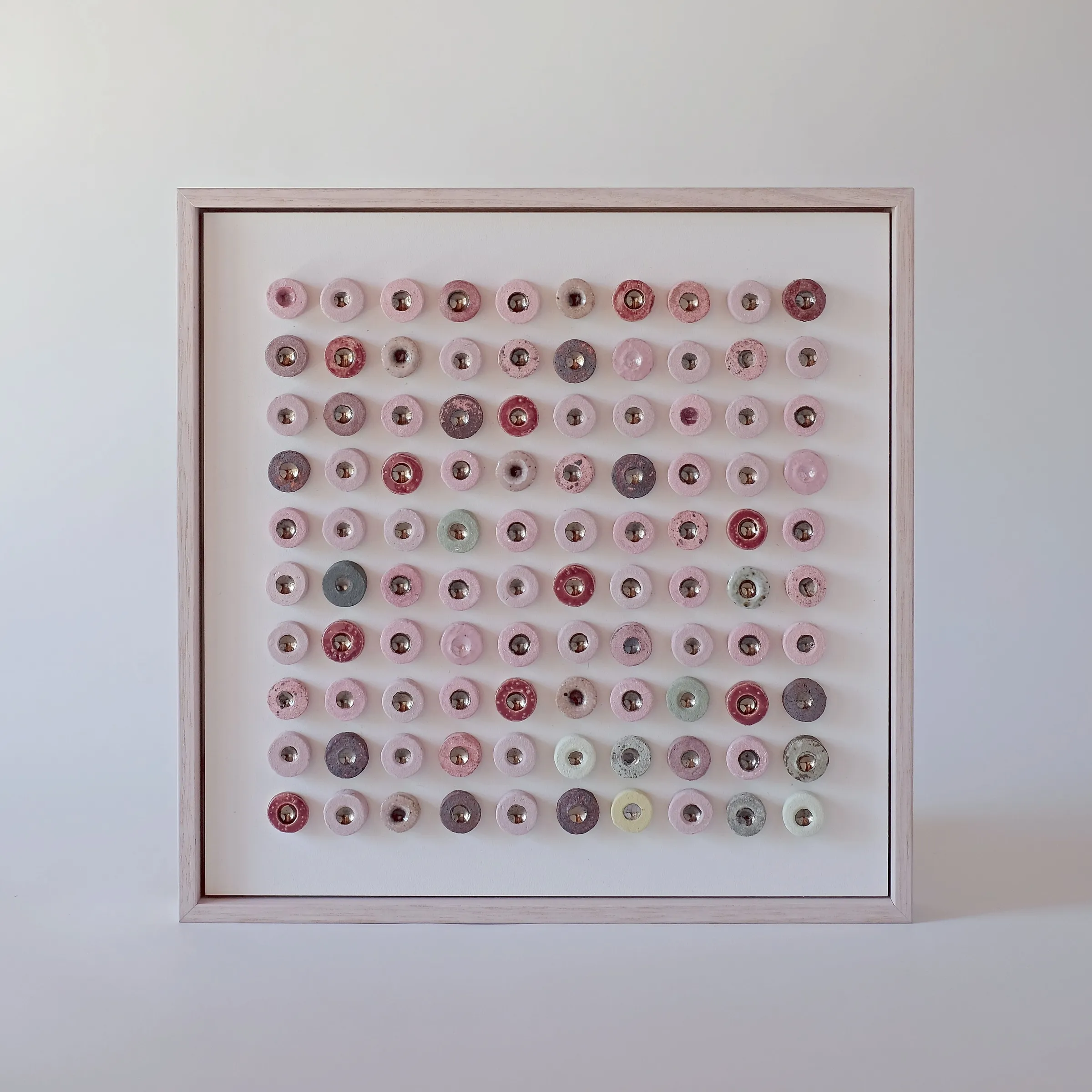 Dot Drift Duo (Patala) by Minaal Lawn, a framed grid of one hundred pink glazed ceramic discs with lustre centres