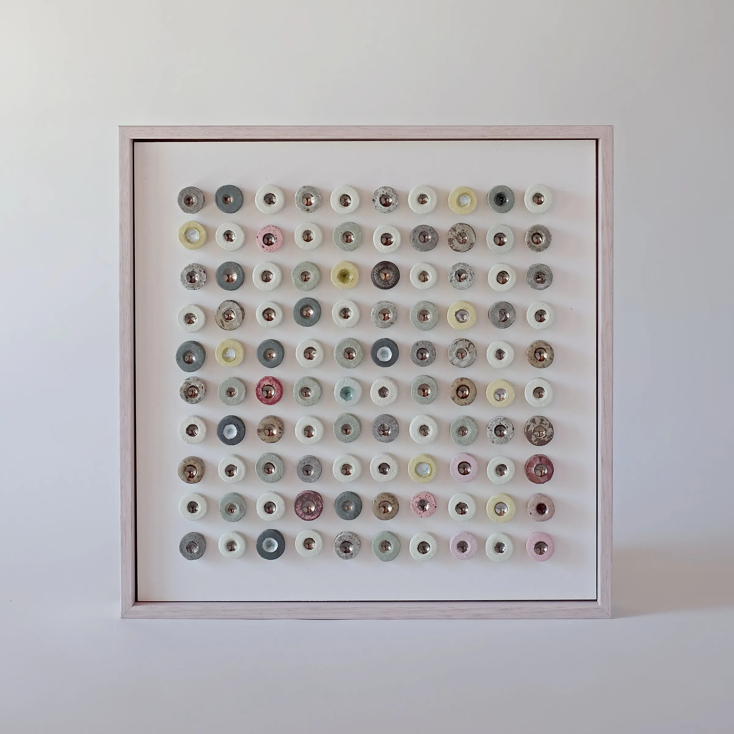 Dot Drift Duo (Patala) by Minaal Lawn, a framed grid of one hundred glazed ceramic discs with lustre centres