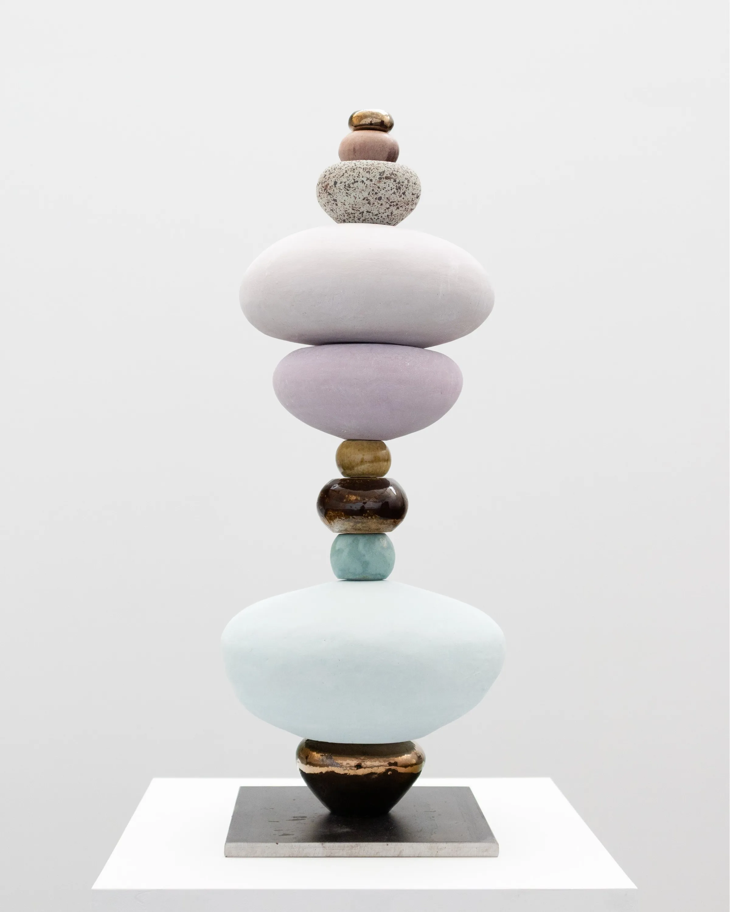 A stack of rounded ceramic forms in lilac and pale blue on a steel base